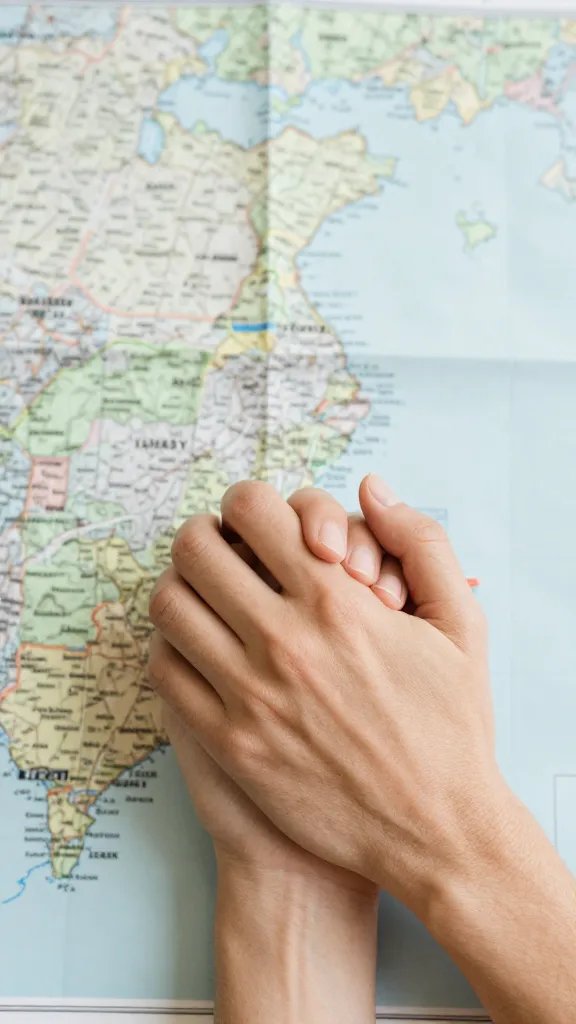 closeup of a couple holding hands over a map of family nearby