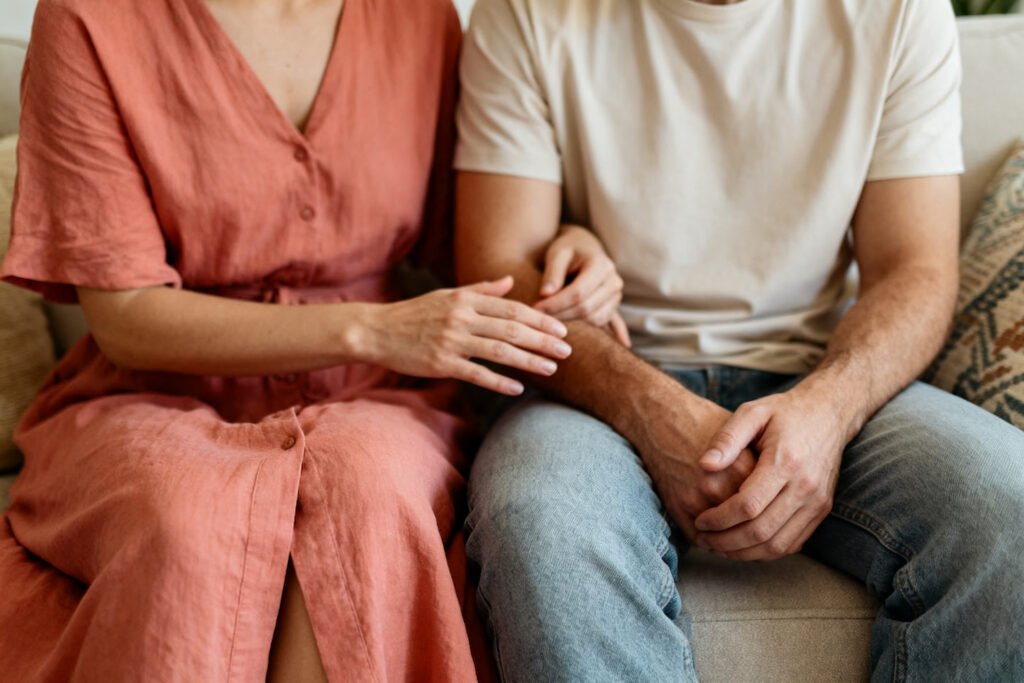 A couple sitting together as one partner gently reaches out to the other