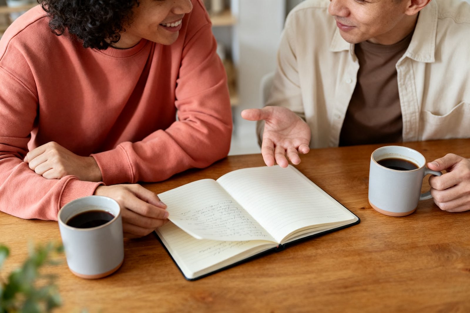 Two people brainstorming with a notebook and coffee