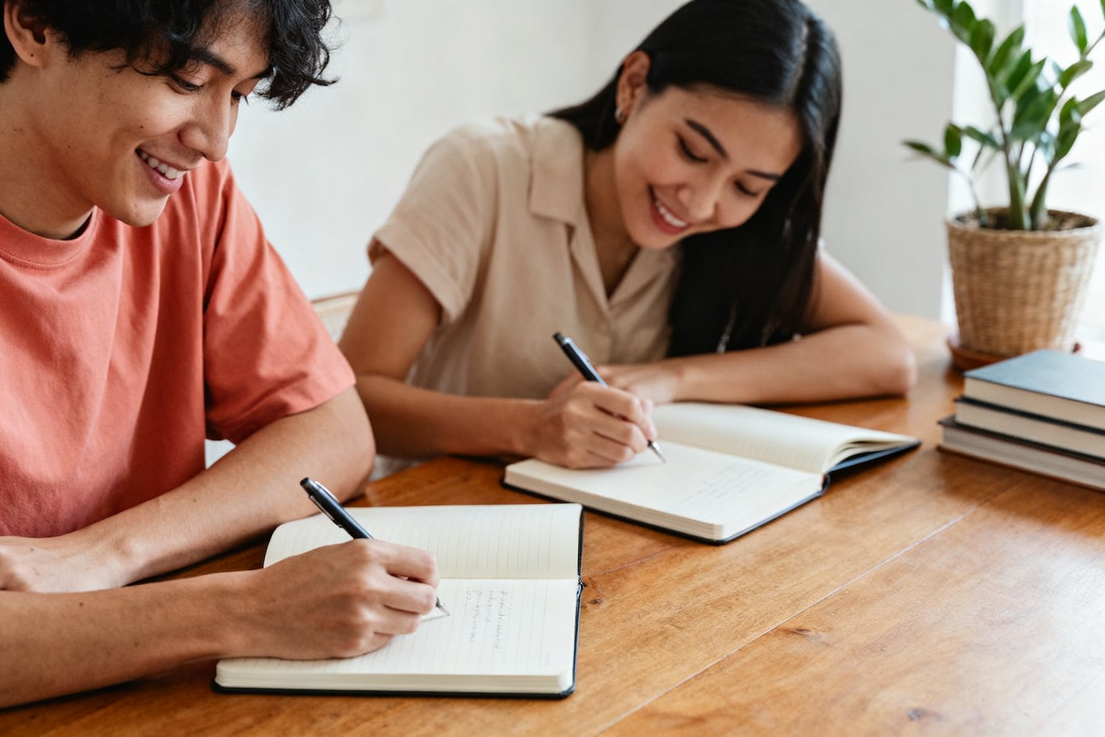 Two people writing in journals together at a table
