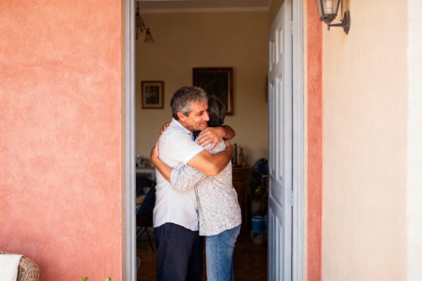 Two people embracing warmly at a doorway
